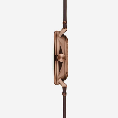 Herrenuhr in Seitenansicht: roségoldfarbenes Gehäuse und braunes Lederarmband.