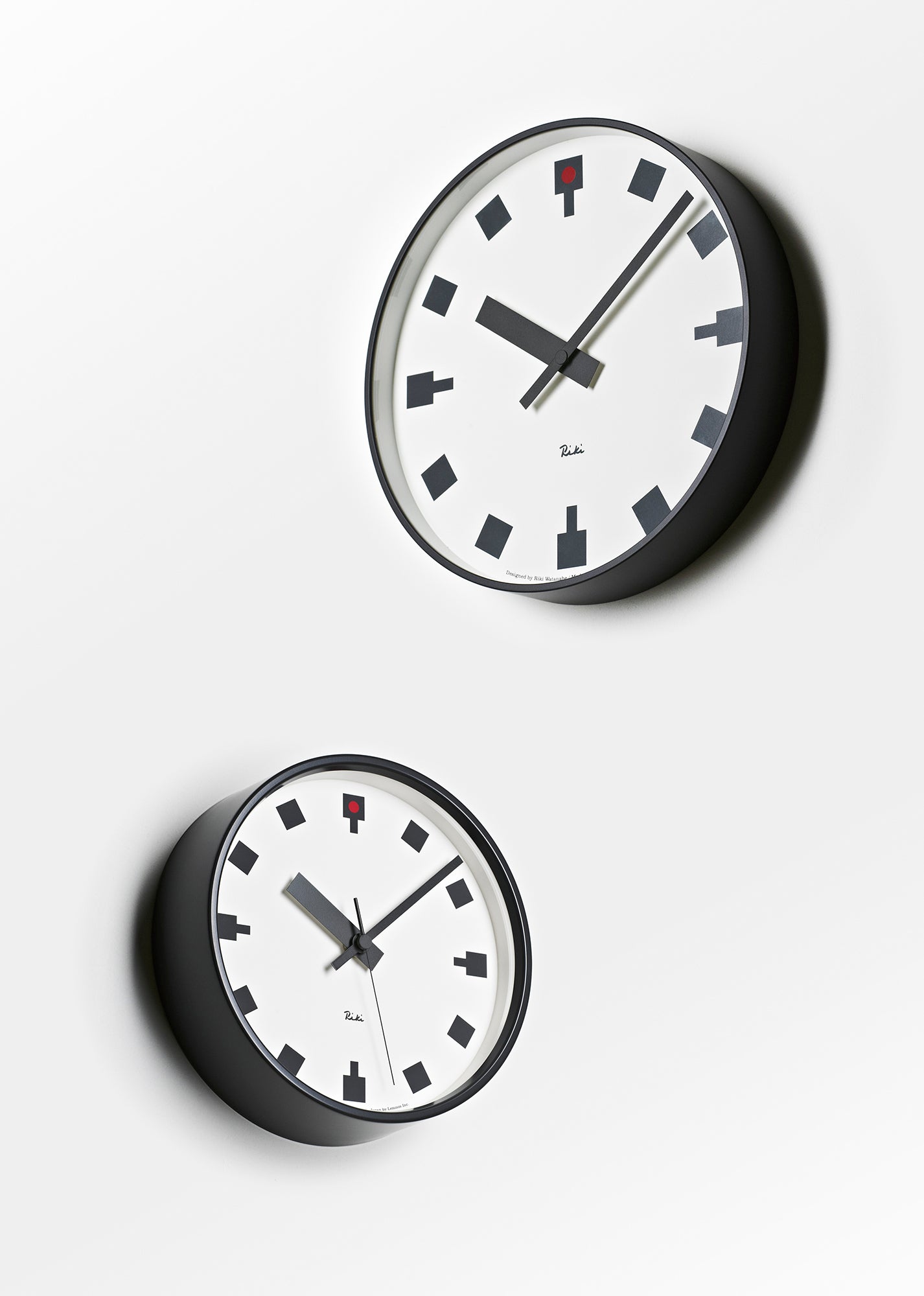 Wanduhr mit weißem Zifferblatt, schwarzen Markierungen, schwarzem Rahmen und roten Details