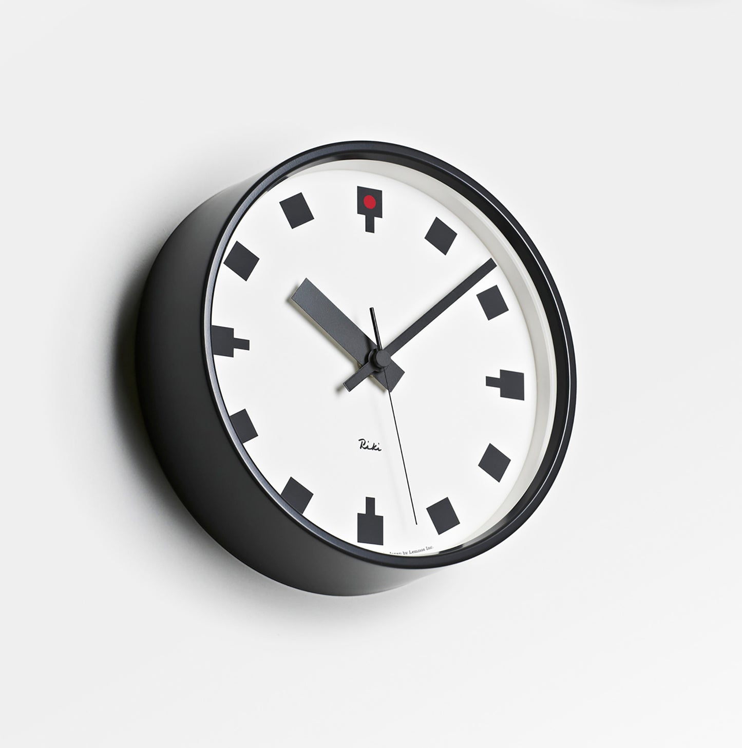 Rundliche Wanduhr mit weißem Zifferblatt, schwarzem Gehäuse und roten Details am Zifferblatt