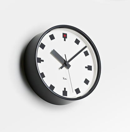 Rundliche Wanduhr mit weißem Zifferblatt, schwarzem Gehäuse und roten Details am Zifferblatt