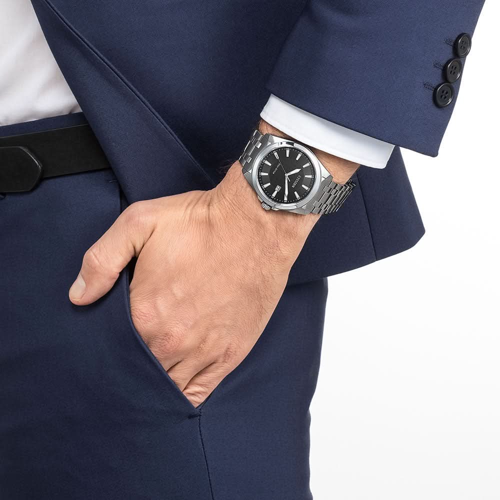 Armbandsur i stål på en handled med svart urtavla och visare