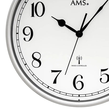 Runde Funk-Wanduhr mit silbernem Rand, schwarzem Ziffernblatt, schwarzen Zeigern und AMS-Logo