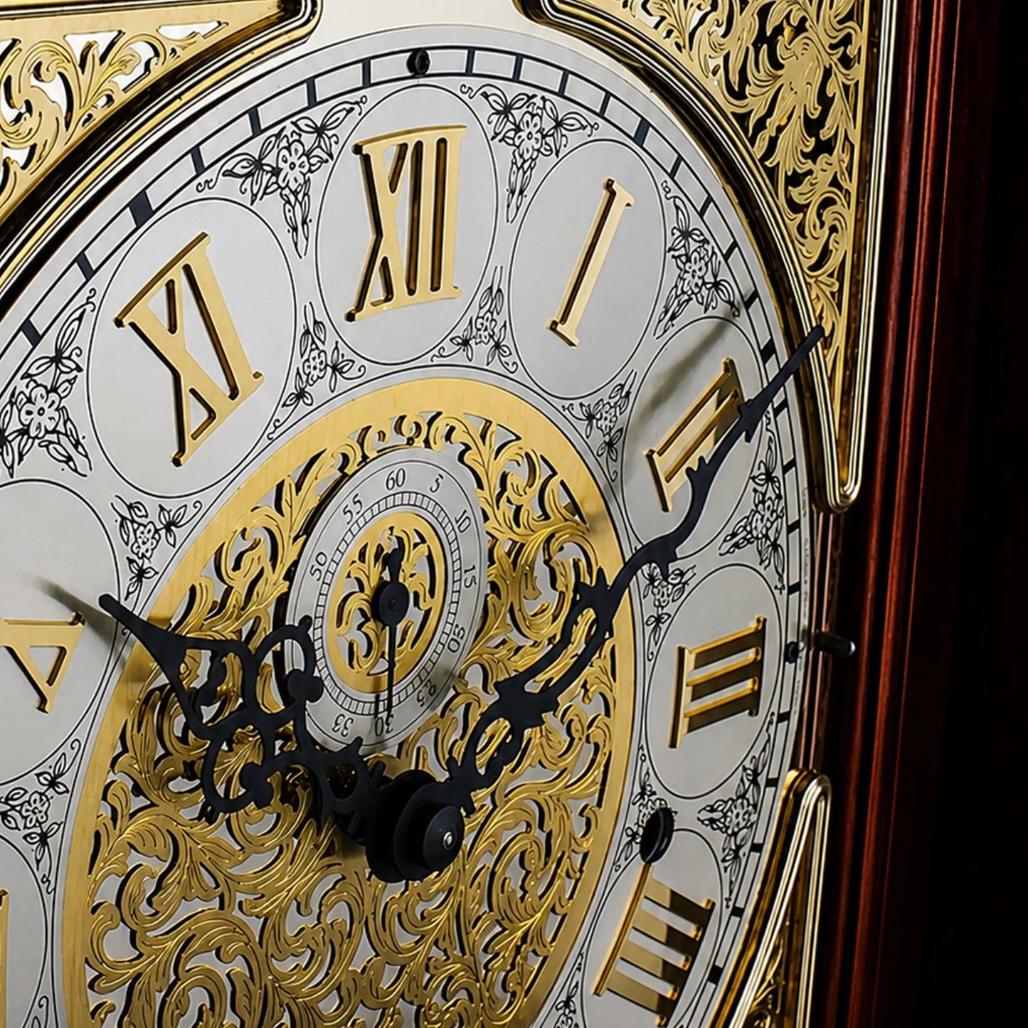 Ausschnitt der Standuhr: weißes Zifferblatt mit goldenen römischen Zahlen und Verzierungen