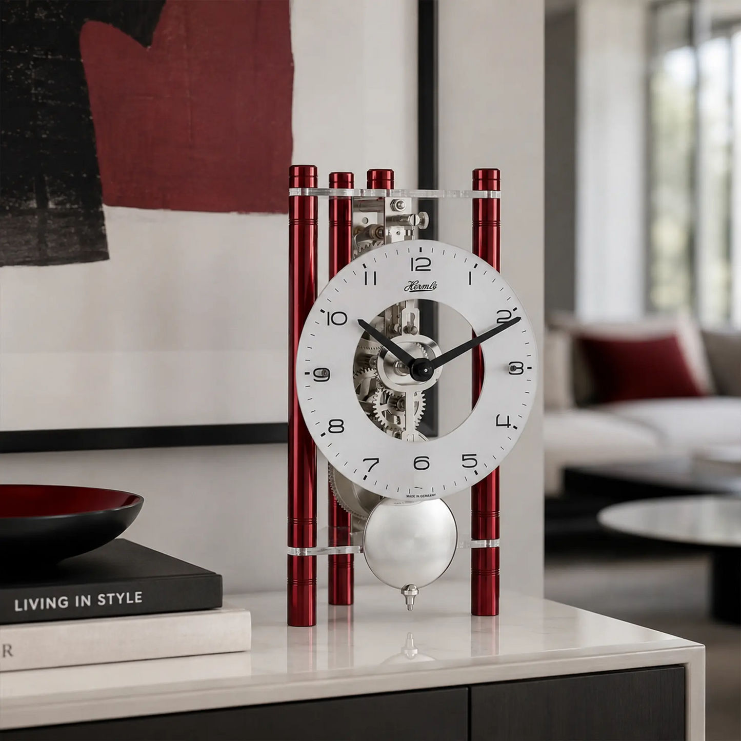 Skelett-Tischuhr mit weißem Ziffernblatt, schwarzem Minutenzeiger und roten Metallstreben