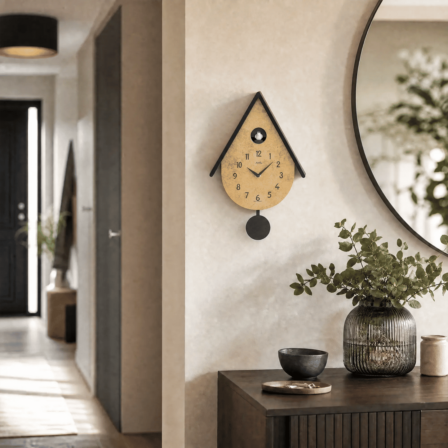 Wanduhr an der Wand mit Vogelmotiv und rundem schwarzem Pendel neben Deko-Konsole