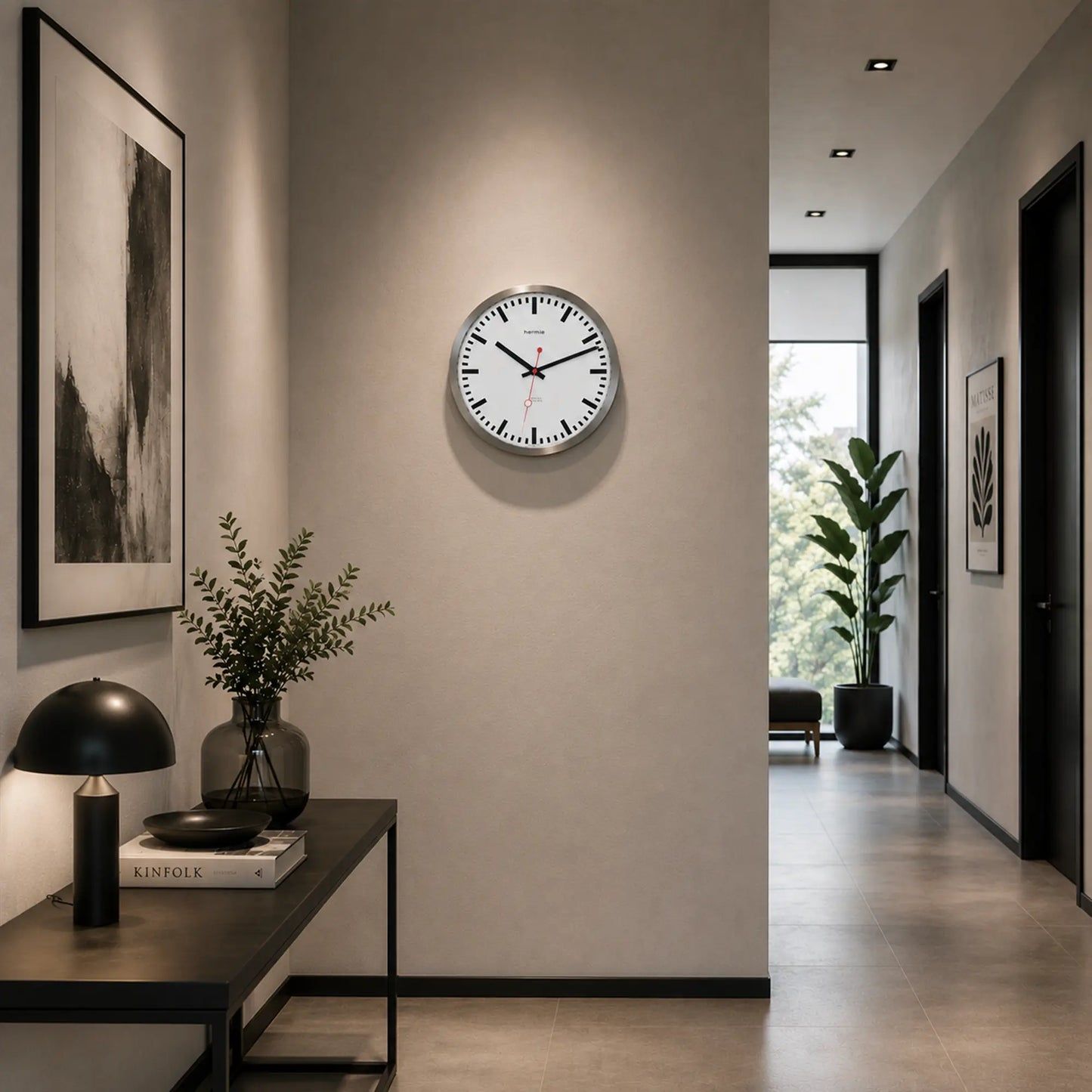 Runde Wanduhr an der Wand mit weißem Zifferblatt, silberner Umrandung, schwarzen Zeigern, roter Sekunde