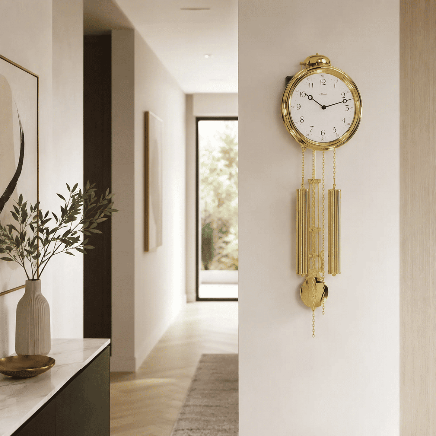 Goldfarbene Wanduhr mit Zierpendeln an der Wand im Flur