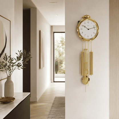 Goldfarbene Wanduhr mit Zierpendeln an der Wand im Flur
