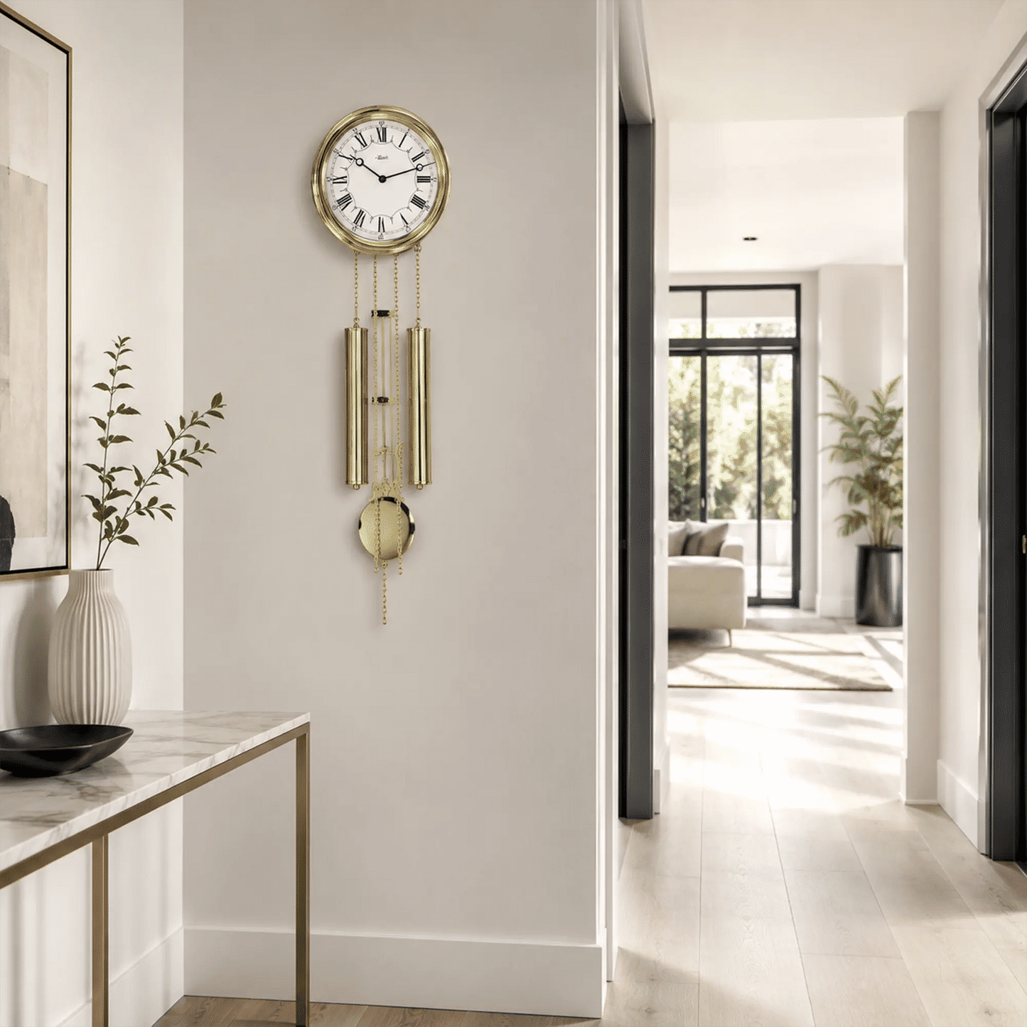 Runde Messing-Wanduhr mit Zifferblatt und goldenen Pendeln an einer weißen Wand