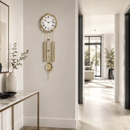 Runde Messing-Wanduhr mit Zifferblatt und goldenen Pendeln an einer weißen Wand