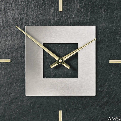 Nahansicht der quadratischen Wanduhr: silberner Rahmen, goldene Zeiger, schwarzes Feld