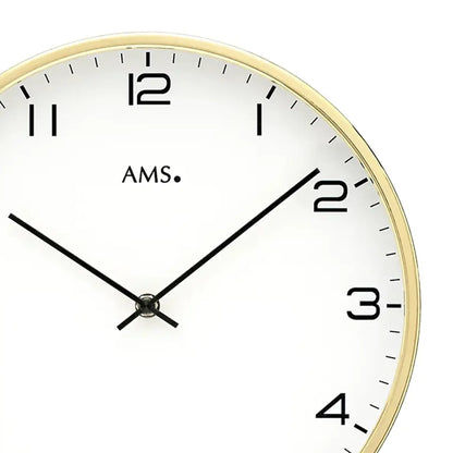 Nahaufnahme der Wanduhr: weißes Zifferblatt mit schwarzen Zeigern und goldfarbener Lünette