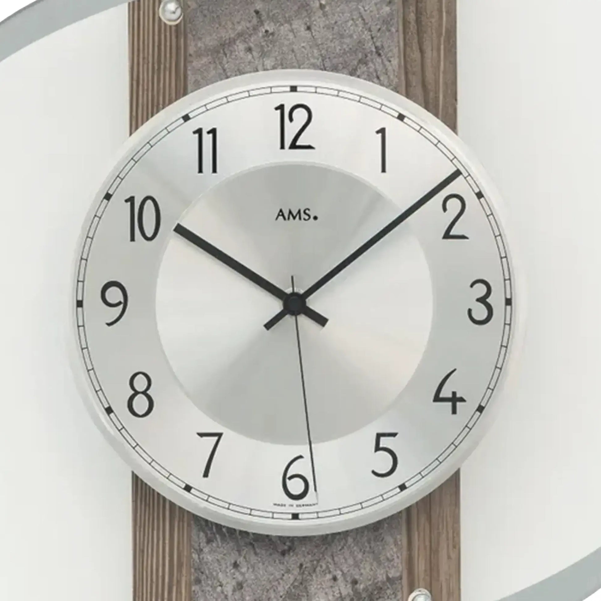 Nahaufnahme Wanduhr: weißes Zifferblatt mit AMS-Schriftzug und schwarzen Zeigern