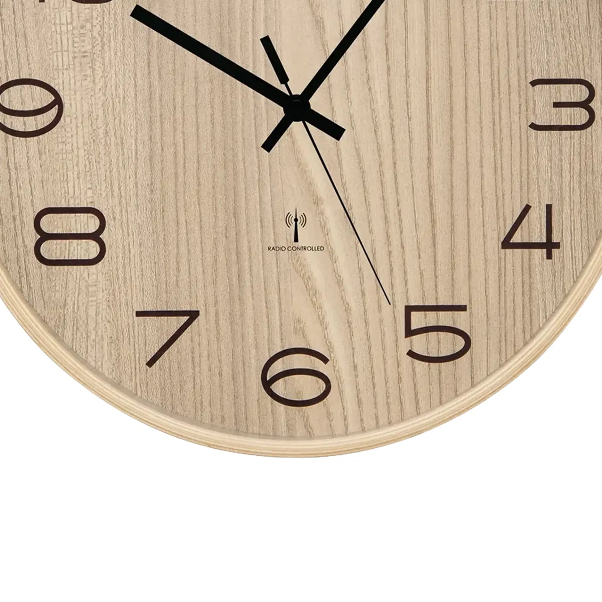 Detail der Wanduhr: Holzoptik, schwarze Zeiger, Aufdruck „RADIO CONTROLLED“