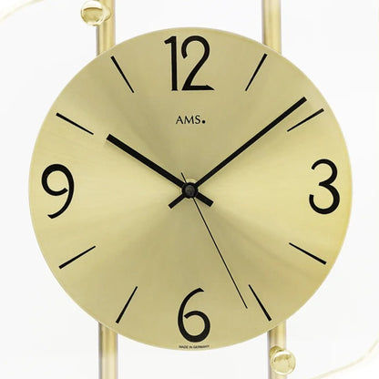 Nahaufnahme AMS Wanduhr: rundes gelbes Ziffernblatt mit Ziffern 12, 9, 3 und Zeigern