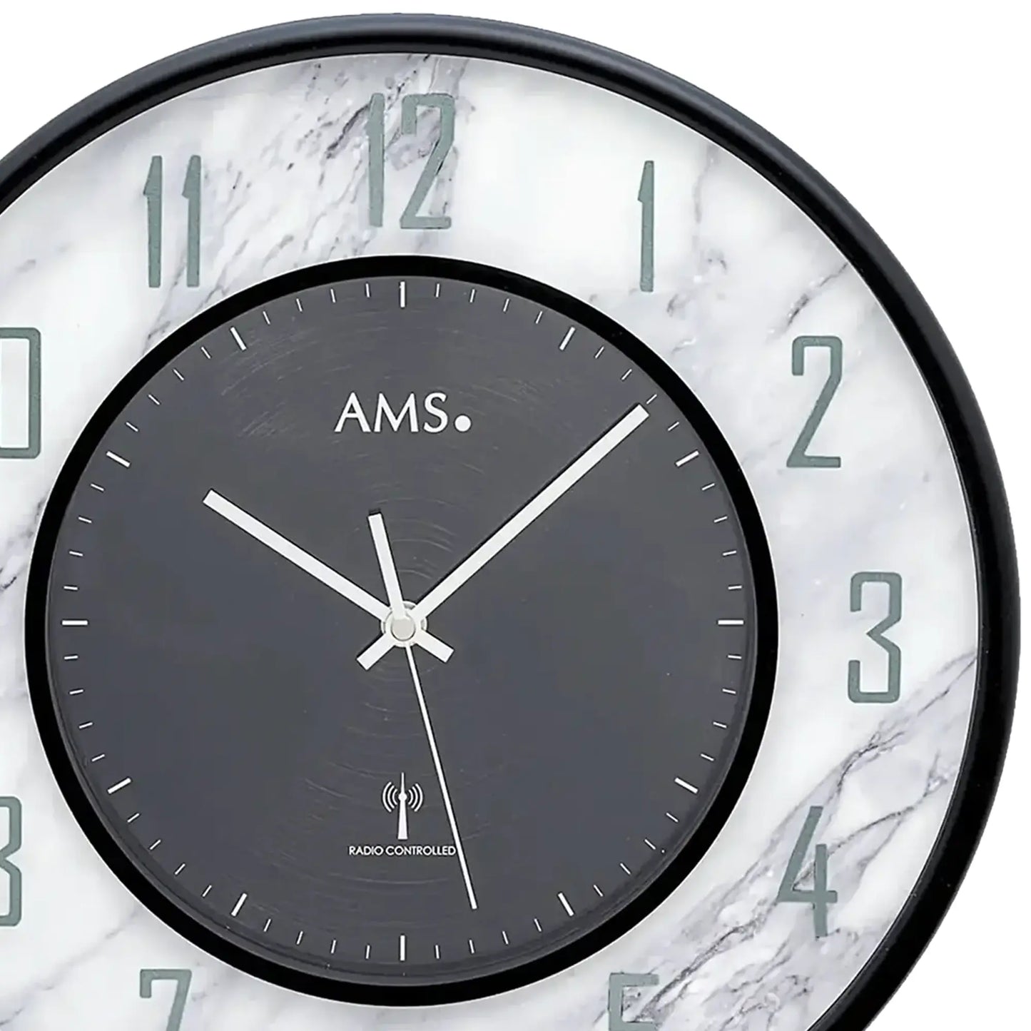 Detailansicht AMS Wanduhr: dunkles Ziffernblatt, weiße Zeiger, Funksymbol „Radio controlled“