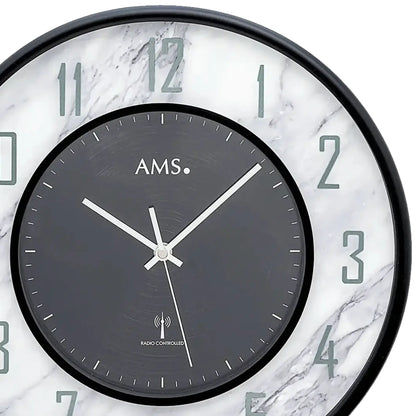 Detailansicht AMS Wanduhr: dunkles Ziffernblatt, weiße Zeiger, Funksymbol „Radio controlled“