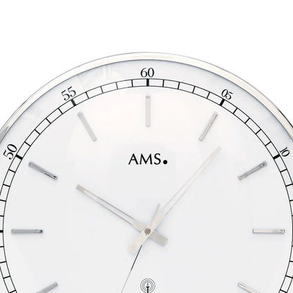 Nahansicht Zifferblatt: runde Wanduhr mit weißem Blatt, silbernen Zeigern und AMS-Logo