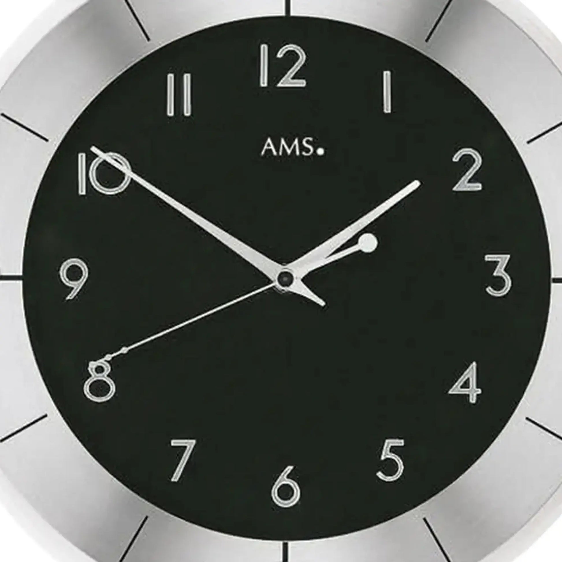 Nahaufnahme: Wanduhr mit schwarzem Ziffernblatt, silbernen Zahlen und Zeigern