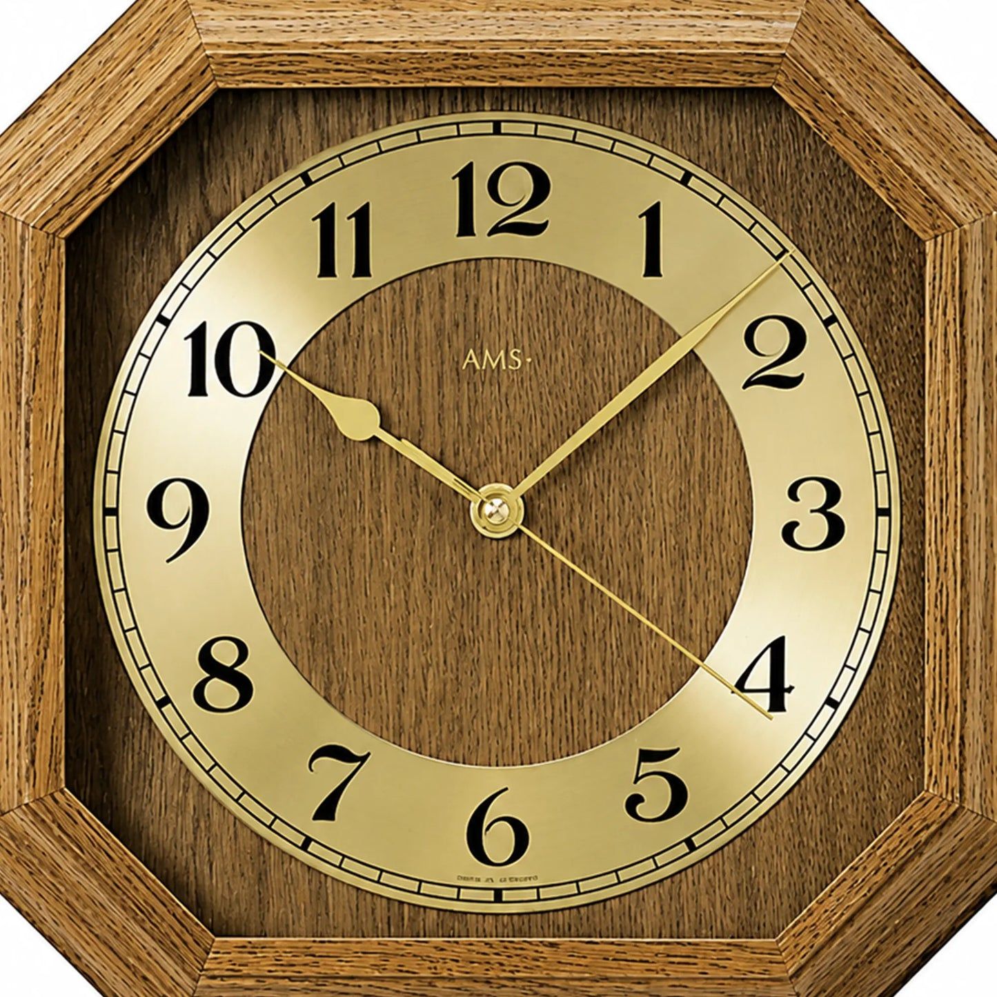 Nahaufnahme Wanduhr: Ziffernring, goldfarbene Zeiger und AMS-Schrift im eichen Holzrahmen