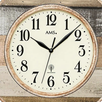 Nahaufnahme des Ziffernblatts einer runden Wanduhr mit AMS-Schrift und schwarzen Zeigern