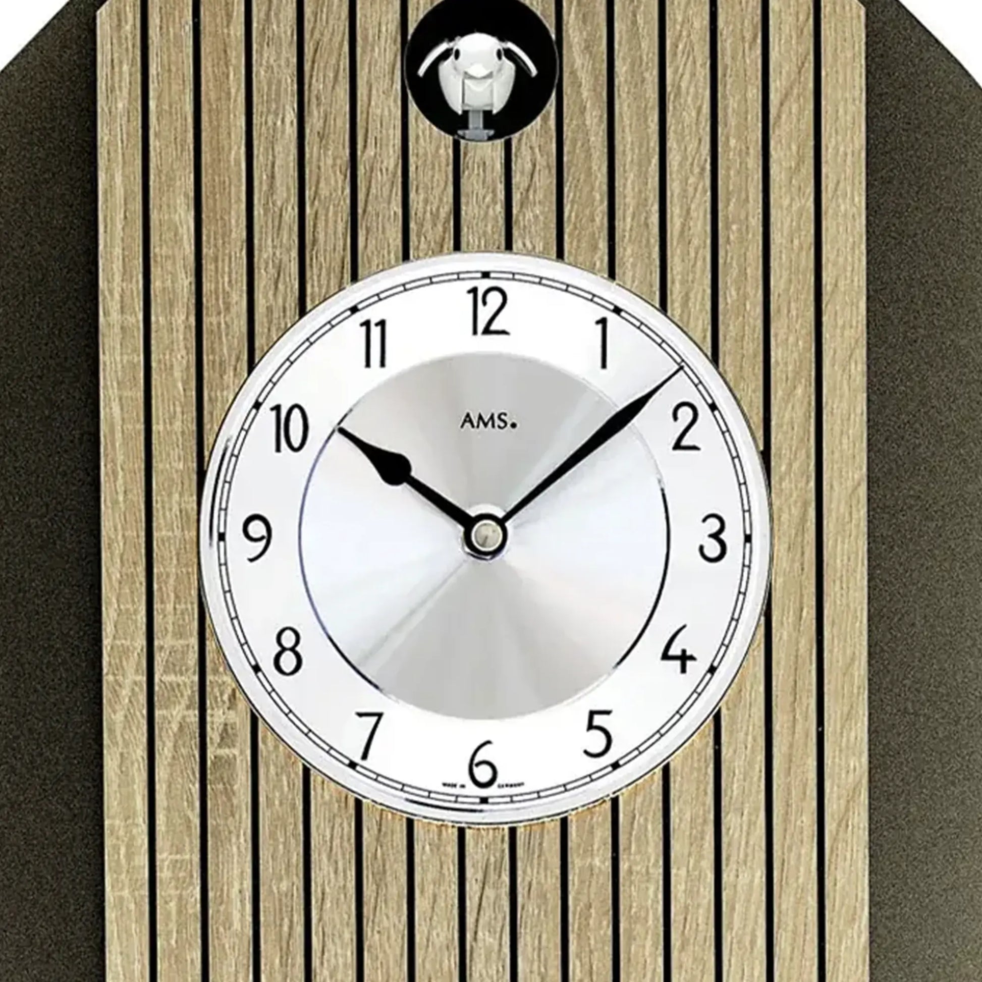 Rundes Ziffernblatt der Wanduhr mit schwarzen Zeigern und „AMS.“-Marke