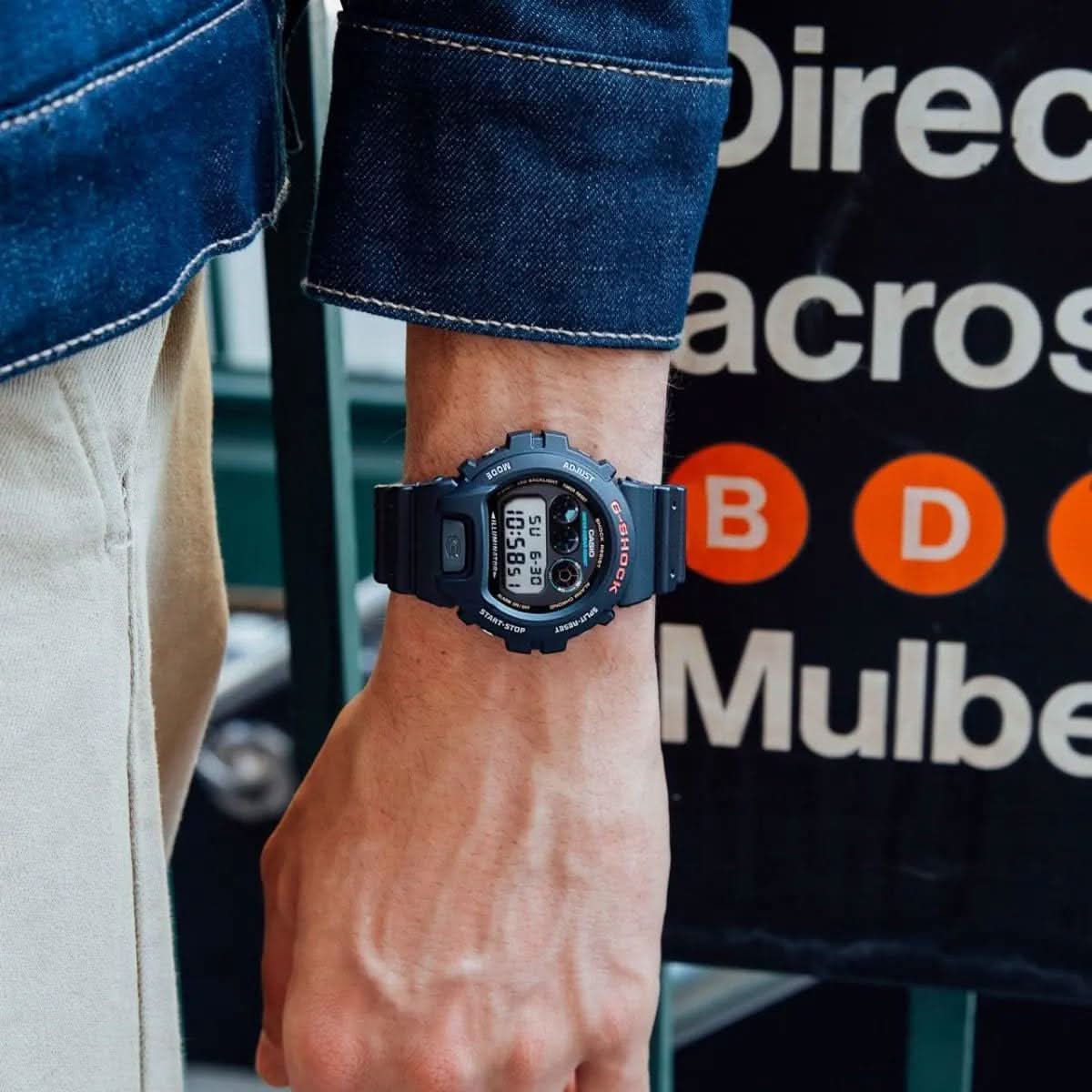 Zegarek Casio G-Shock na nadgarstku, czarny pasek i tarcza na tle koszuli jeansowej