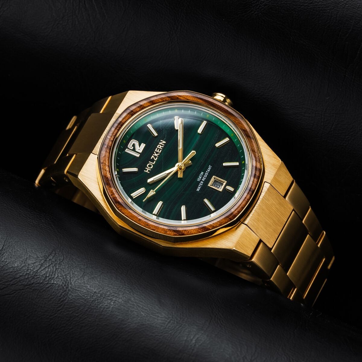 Herren-Armbanduhr mit grünem Malachit-Zifferblatt und goldfarbenem Edelstahlarmband auf dunklem Untergrund