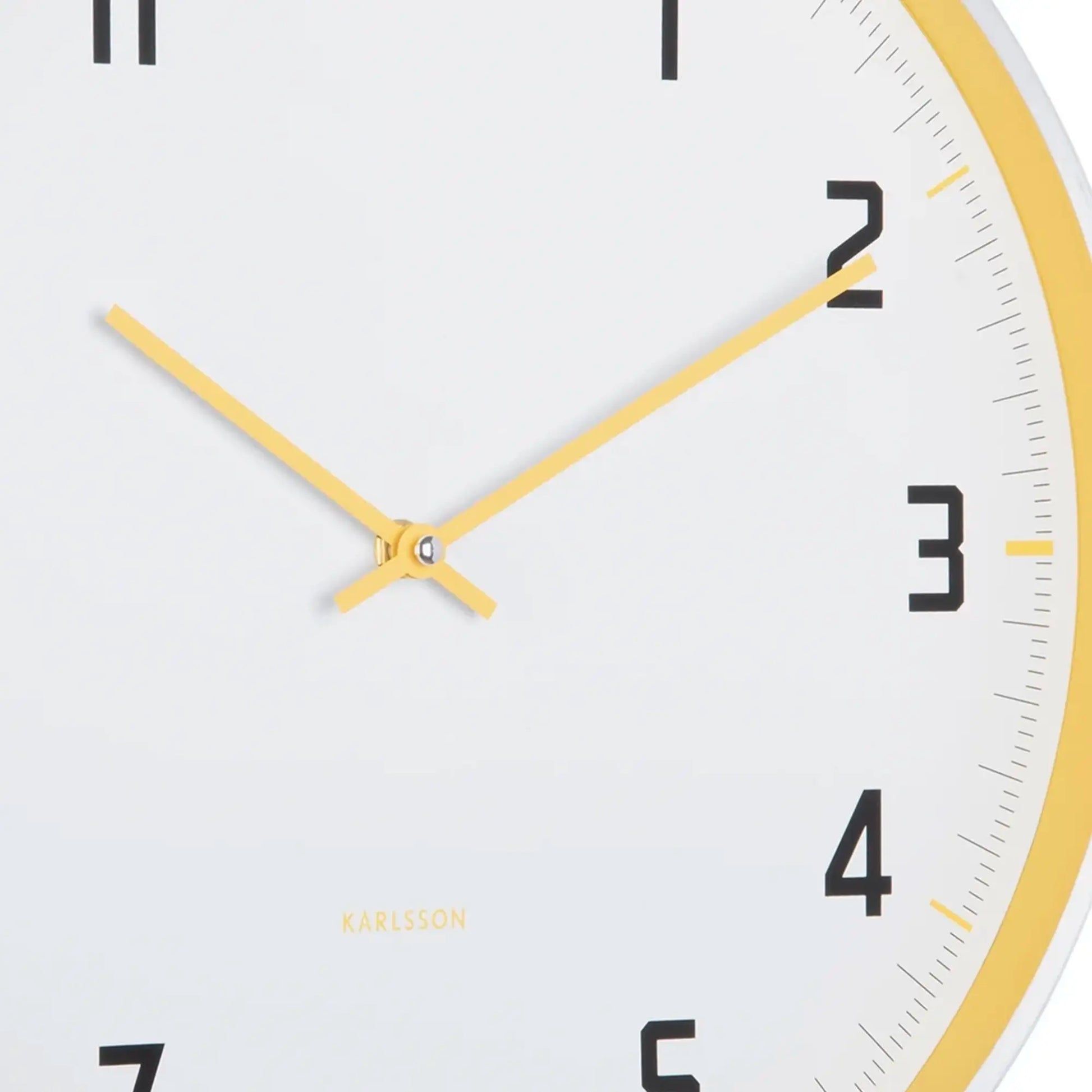 Nahaufnahme: Karlsson Wanduhr-Ziffernblatt mit gelben Zeigern und schwarzen Zahlen
