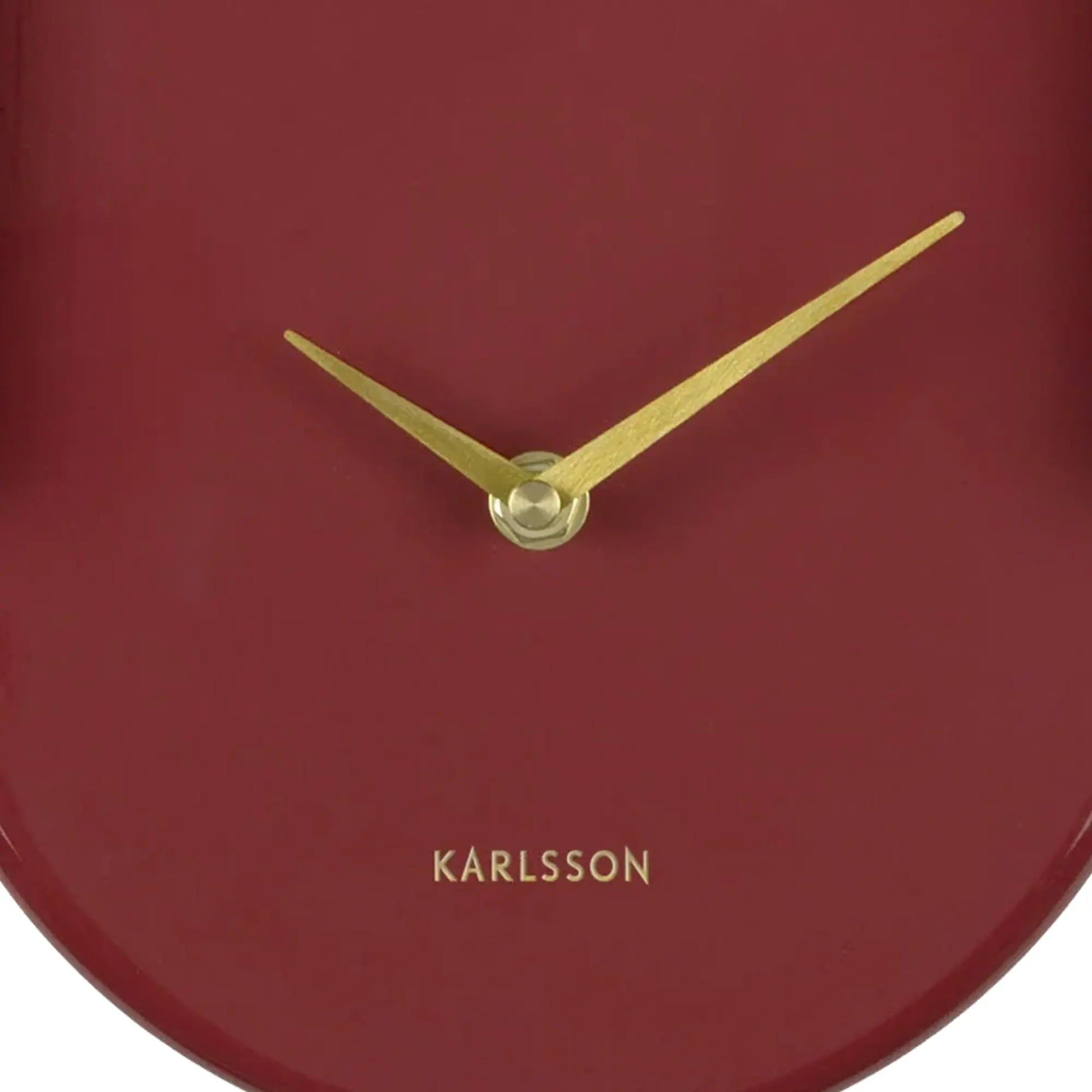Nahaufnahme burgunderrote Wanduhr mit goldenen Zeigern und KARLSSON-Schriftzug