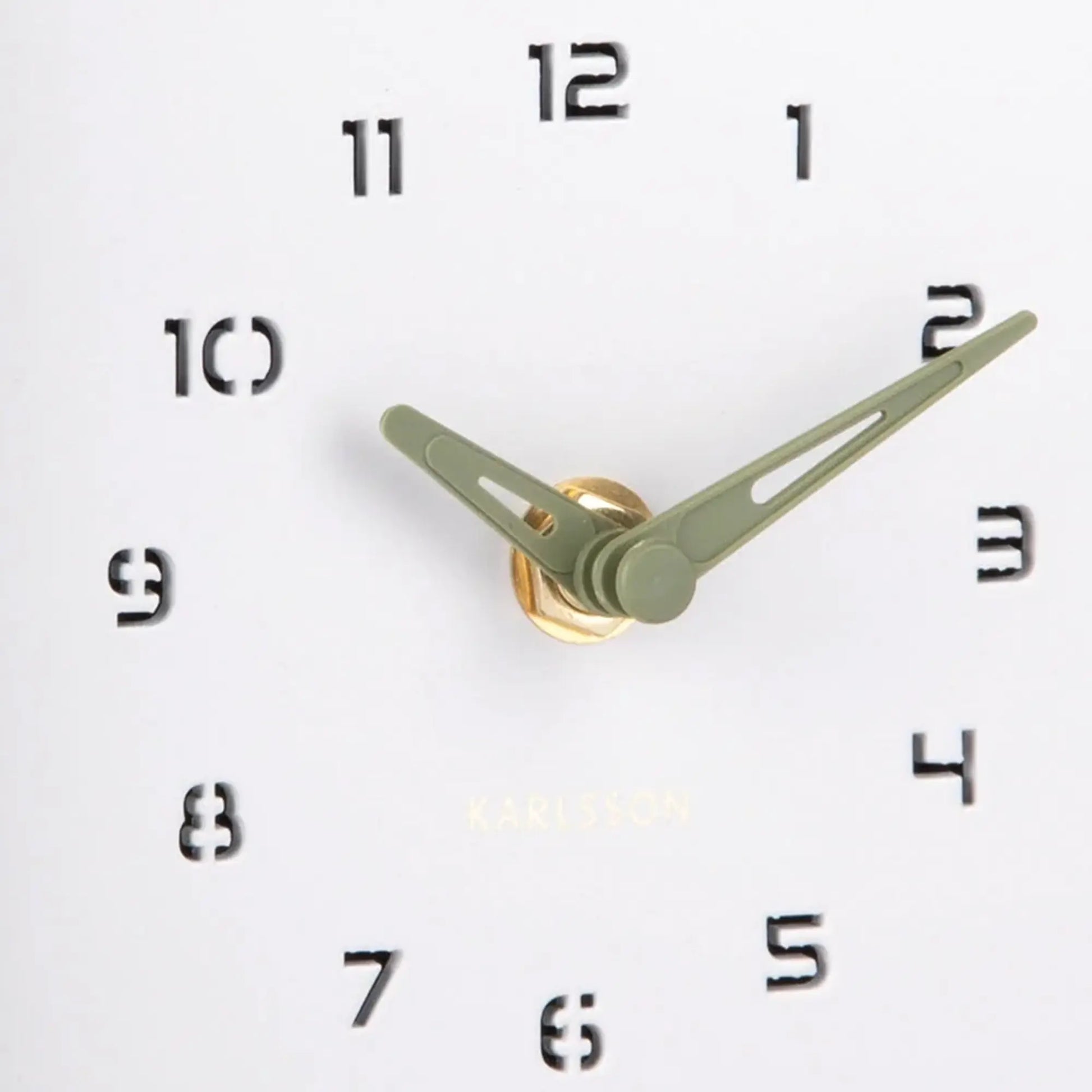 Nahaufnahme Wanduhr: grüne Zeiger, schwarze Ziffern und goldfarbenes Uhrwerk
